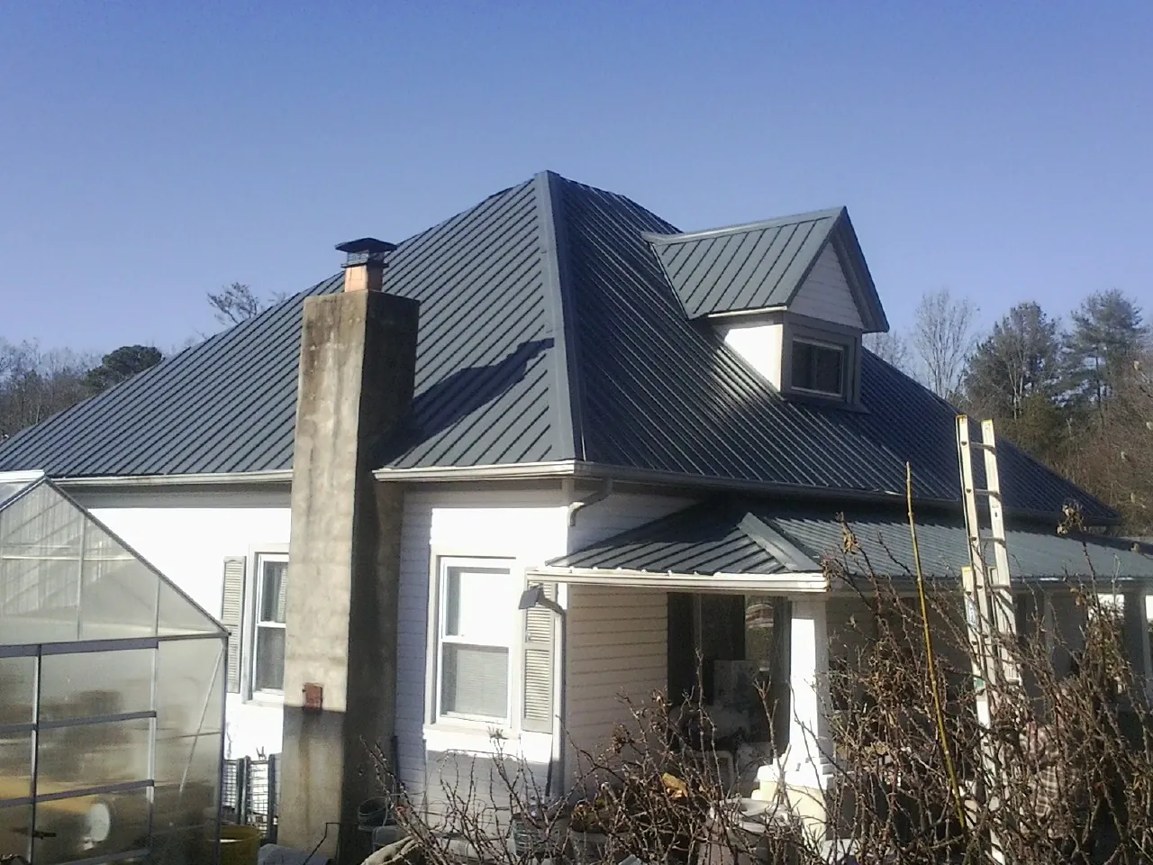 Dark blue standing seam metal roof on a white farmhouse with dormer — Slate & Tile Roof Repair by Roofing Brothers in Andover