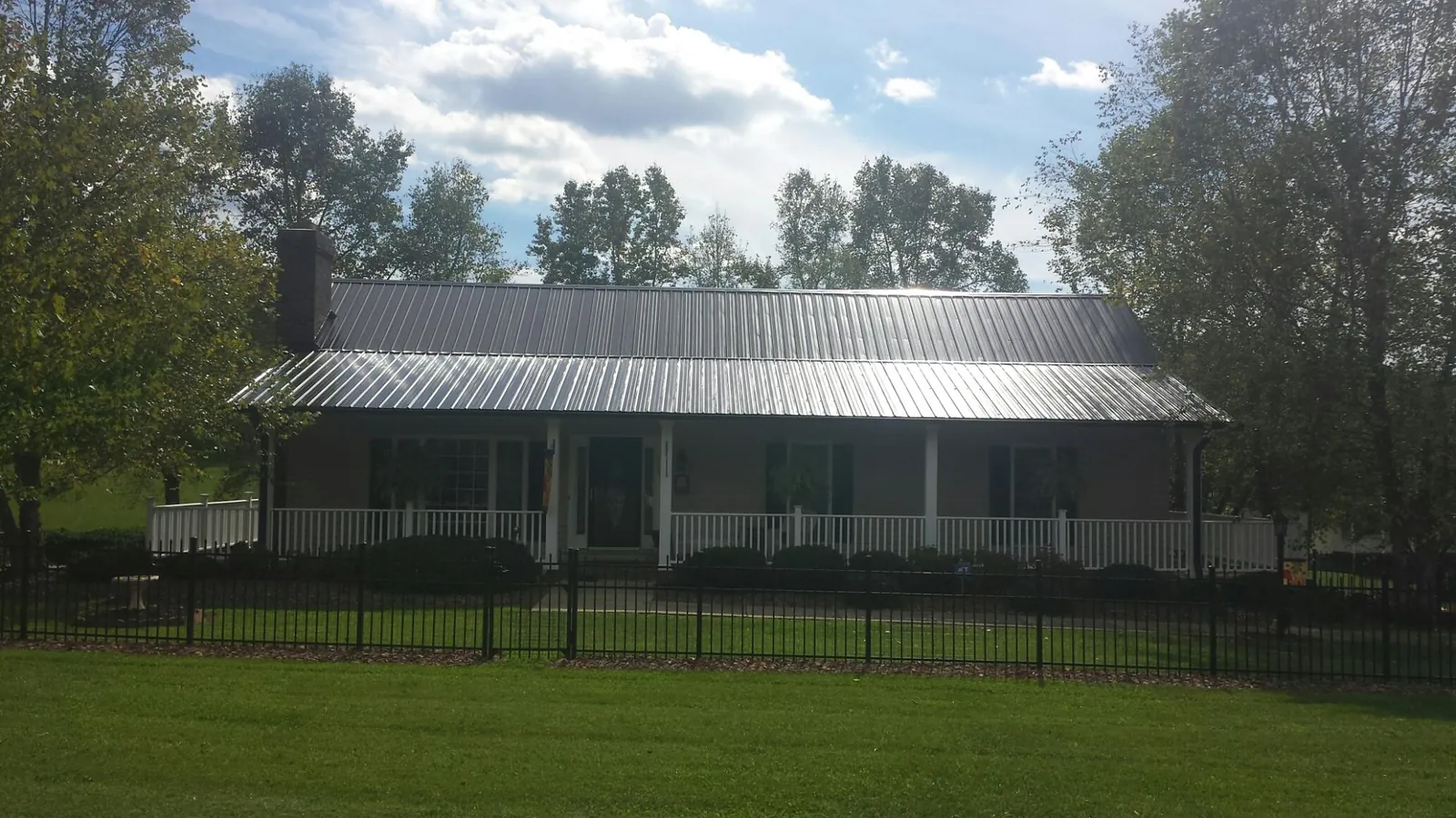 Gray metal roof on a brick ranch with a full width front porch — Gutter Guard Installation work by our crew in Andover
